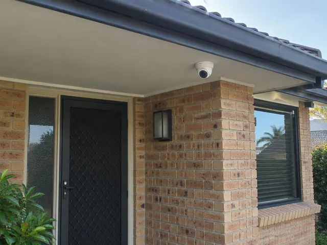 Exterior brick home entry with a dome CCTV camera mounted under the eaves in Hope Island
